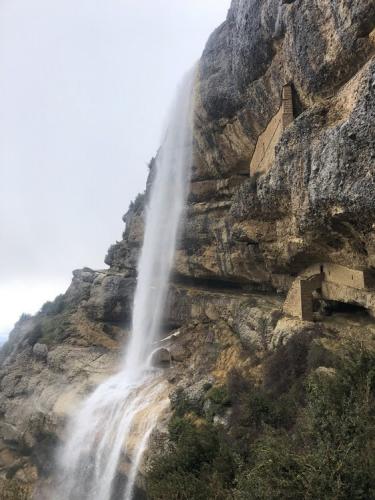 The path follows the rock ledge behind the waterfall